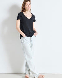 Person wearing a black t-shirt and light gray pants against a white background