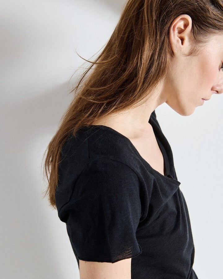 Woman wearing a black top against a plain background
