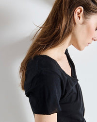 Woman wearing a black top against a plain background