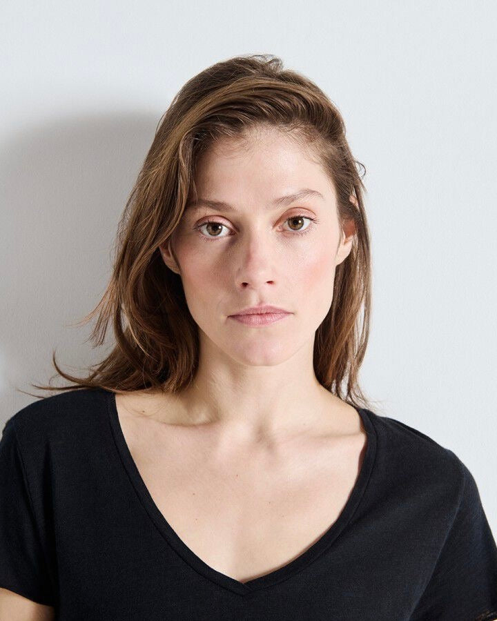 Woman wearing a black v neck top against a plain background