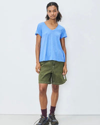 Person wearing a blue t-shirt and green shorts against a white background