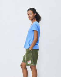 Person wearing a blue shirt and green shorts on a white background