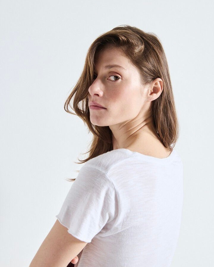 Woman wearing a white t-shirt against a plain background