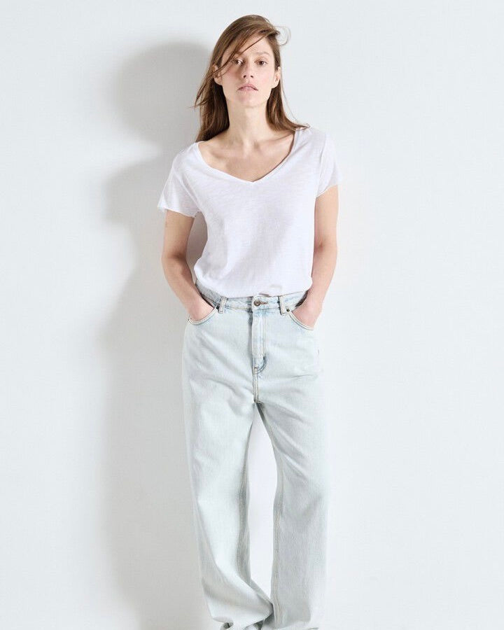 Person wearing a white t-shirt and light blue jeans against a plain background