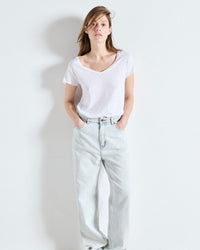 Person wearing a white t-shirt and light blue jeans against a plain background