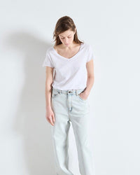 Person wearing a white t-shirt and light blue jeans on a plain background