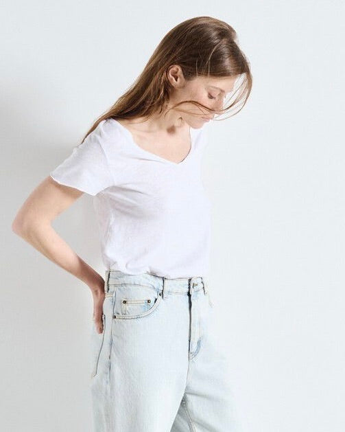 Person wearing a white t-shirt and light blue jeans on a plain background