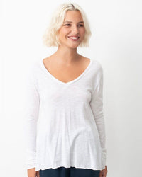 Woman wearing a white long-sleeve top on a plain background