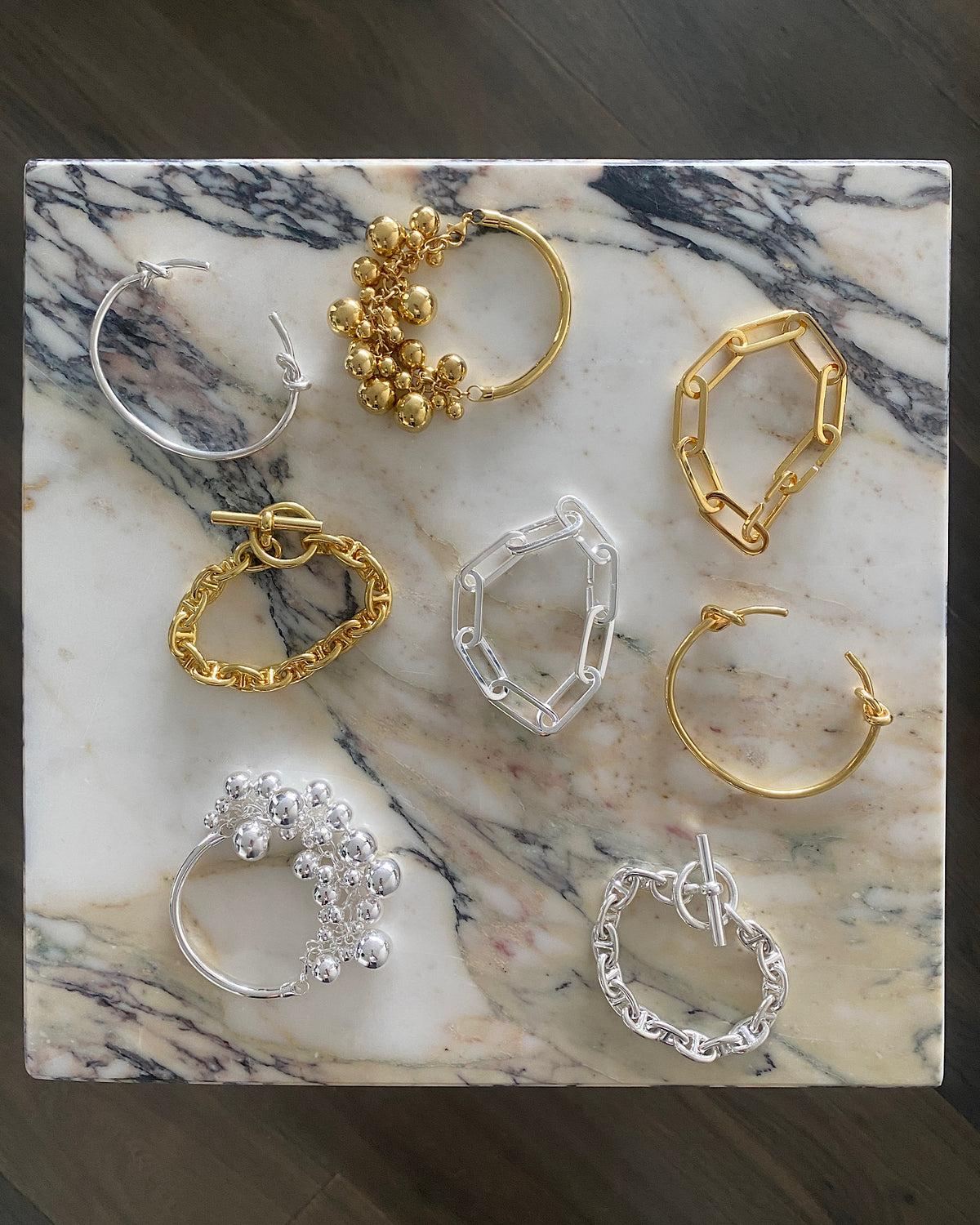 a selection of silver and gold bracalets sit on a marble plinth