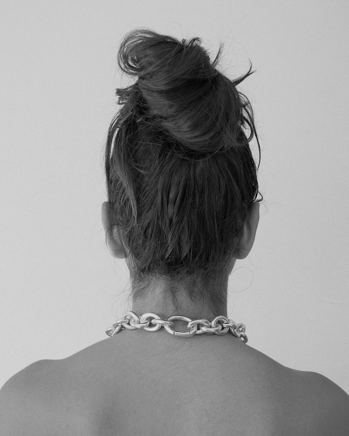 the back view of a model wearing a chunky chain necklace