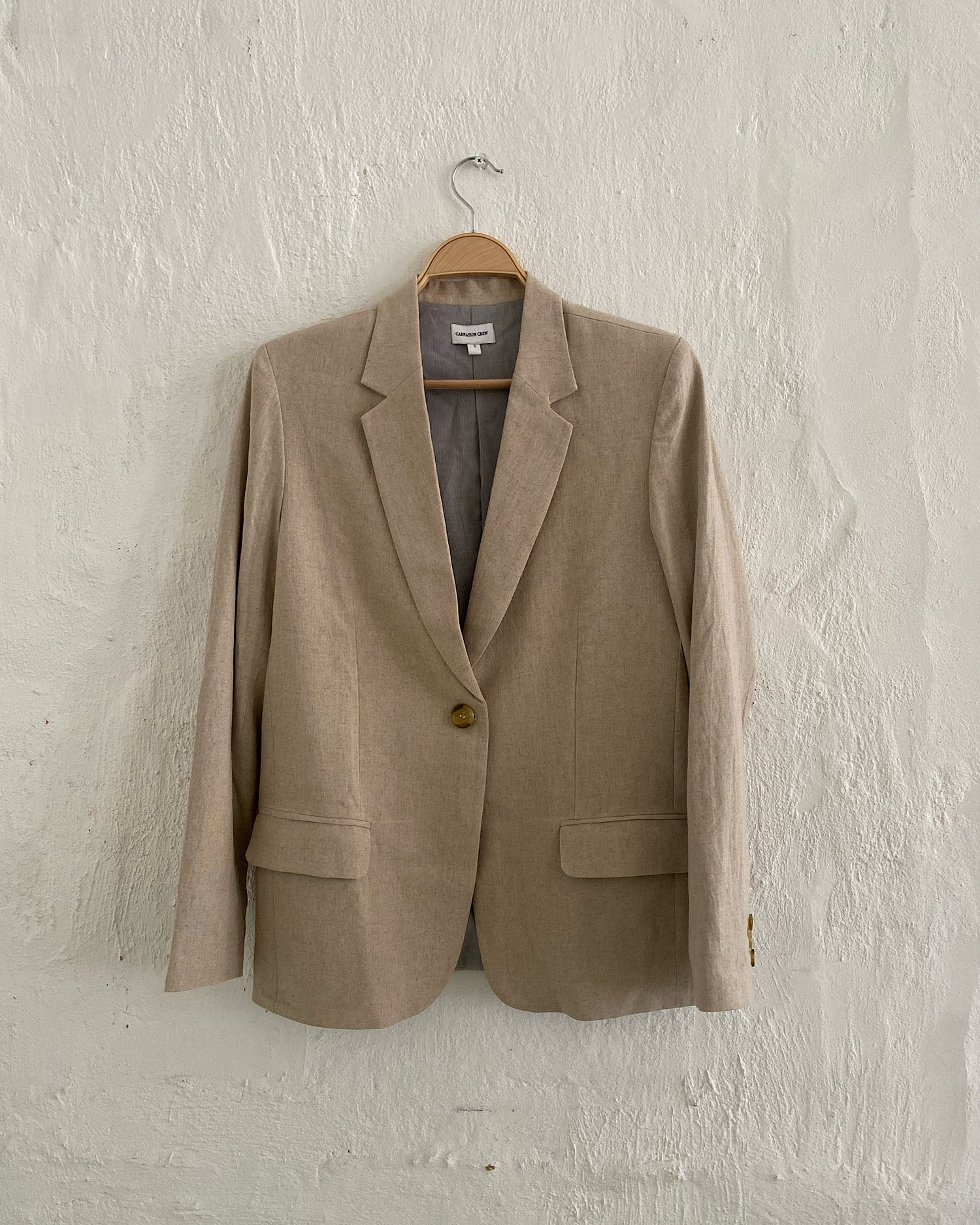 Simple linen blazer sits on a hanger. Available at Sydney Studio The Pared Store