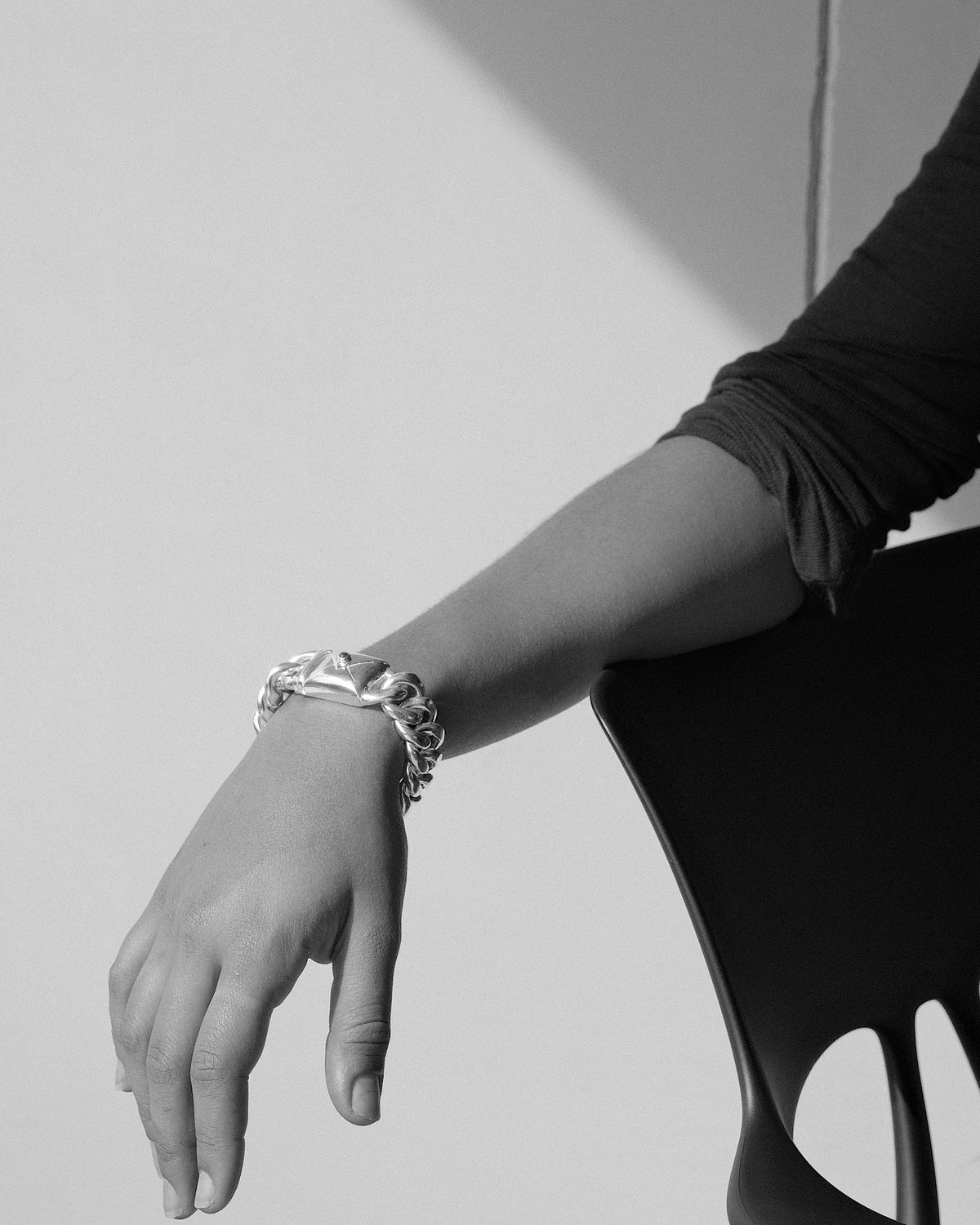 model wears a thick chain bracelet with an envelope clasp detail