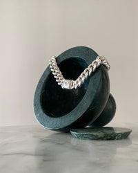 cuban link necklace rests on a green marble vessel