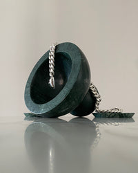 cuban link necklace rests on a green marble vessel