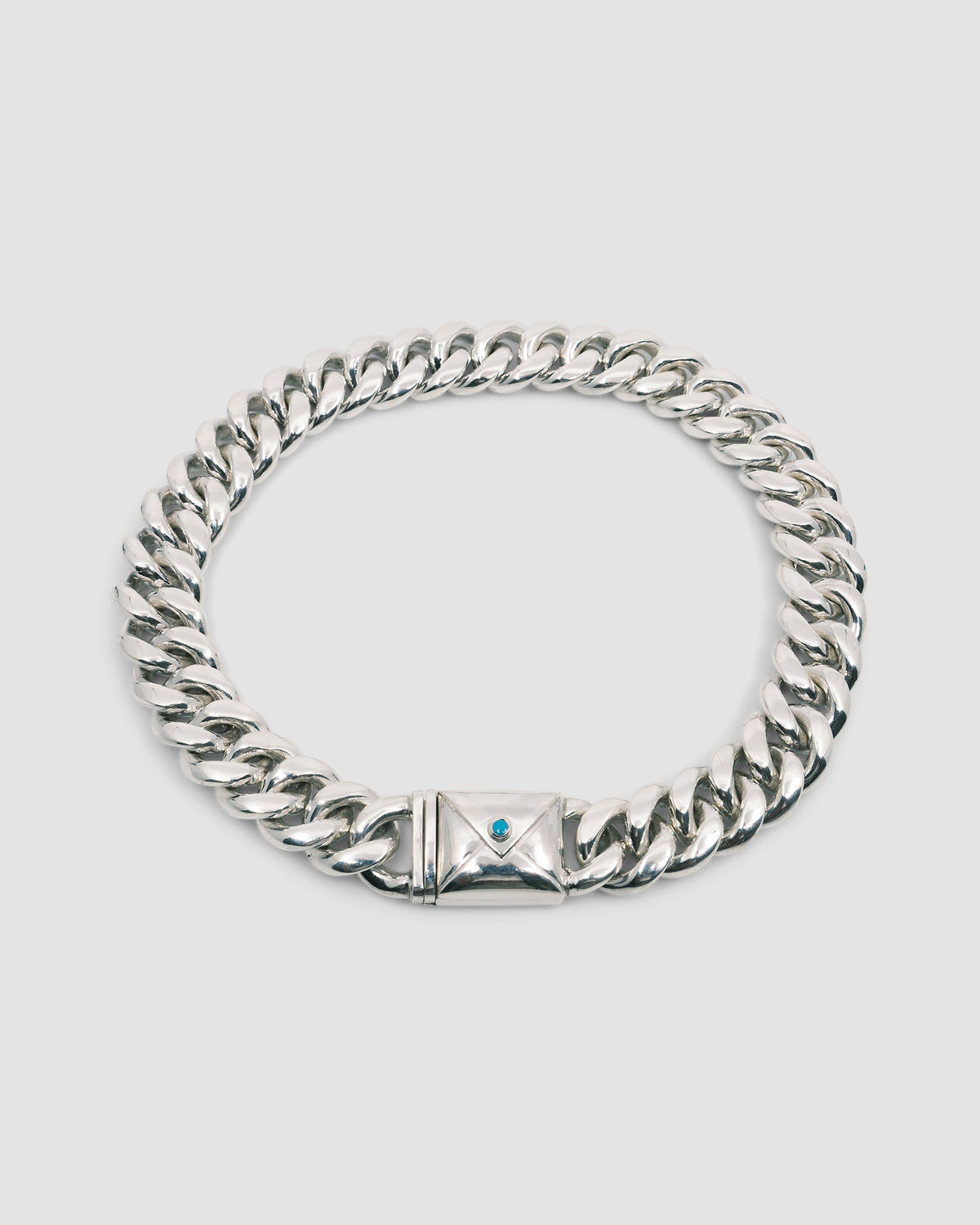 a large silver cuban link necklace with an envelope clasp with a blue stone