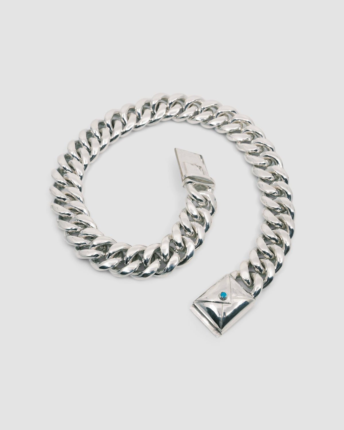 a large silver cuban link necklace with an envelope clasp with a blue stone