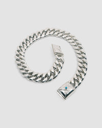 a large silver cuban link necklace with an envelope clasp with a blue stone