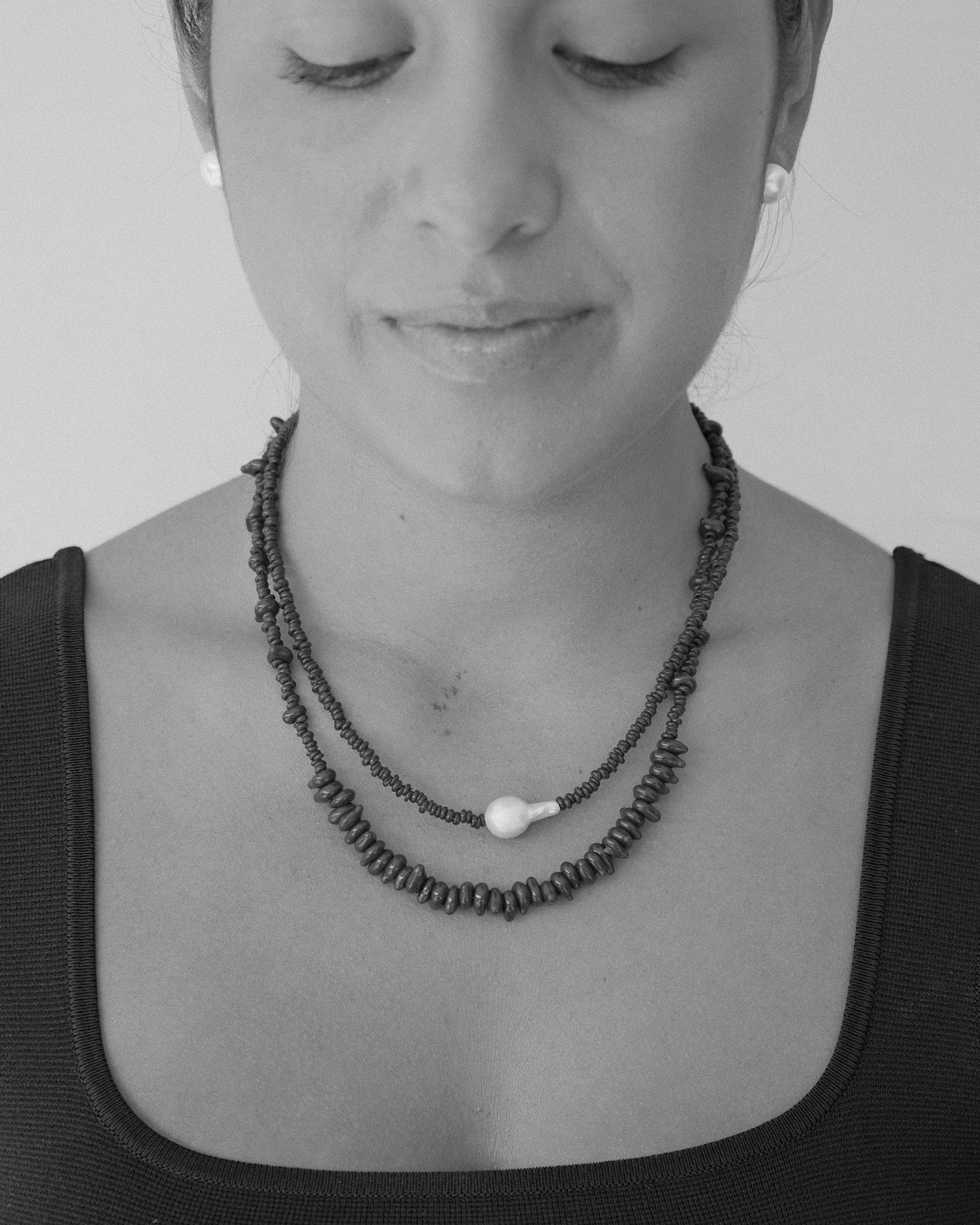 model wears two glass bead necklaces - one with a baroque pearl