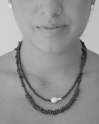 model wears two glass bead necklaces - one with a baroque pearl