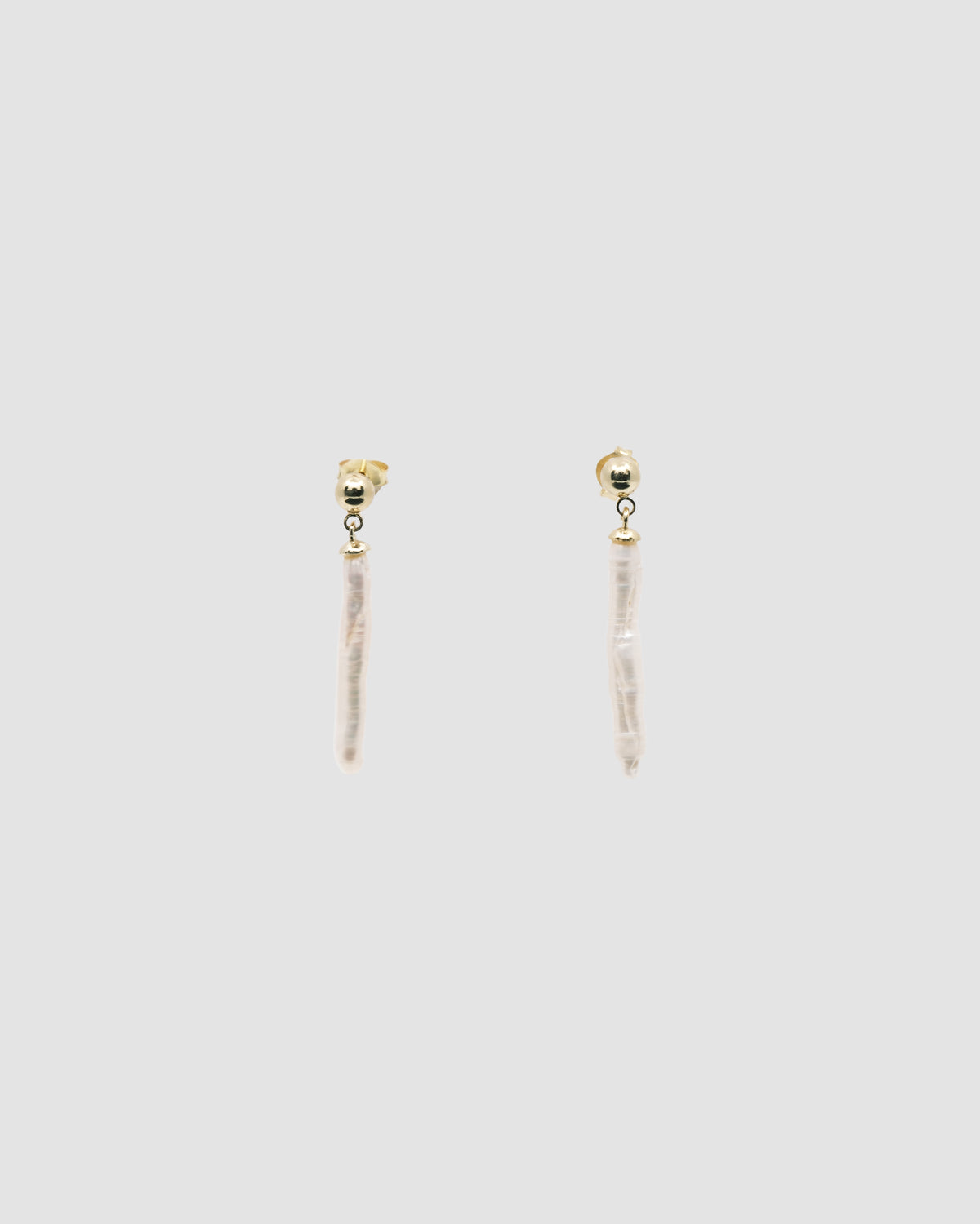 long skinny pearls dangle from a small gold stud earring