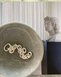 Large chain silver bracelet in a stone bowl on a magazine page