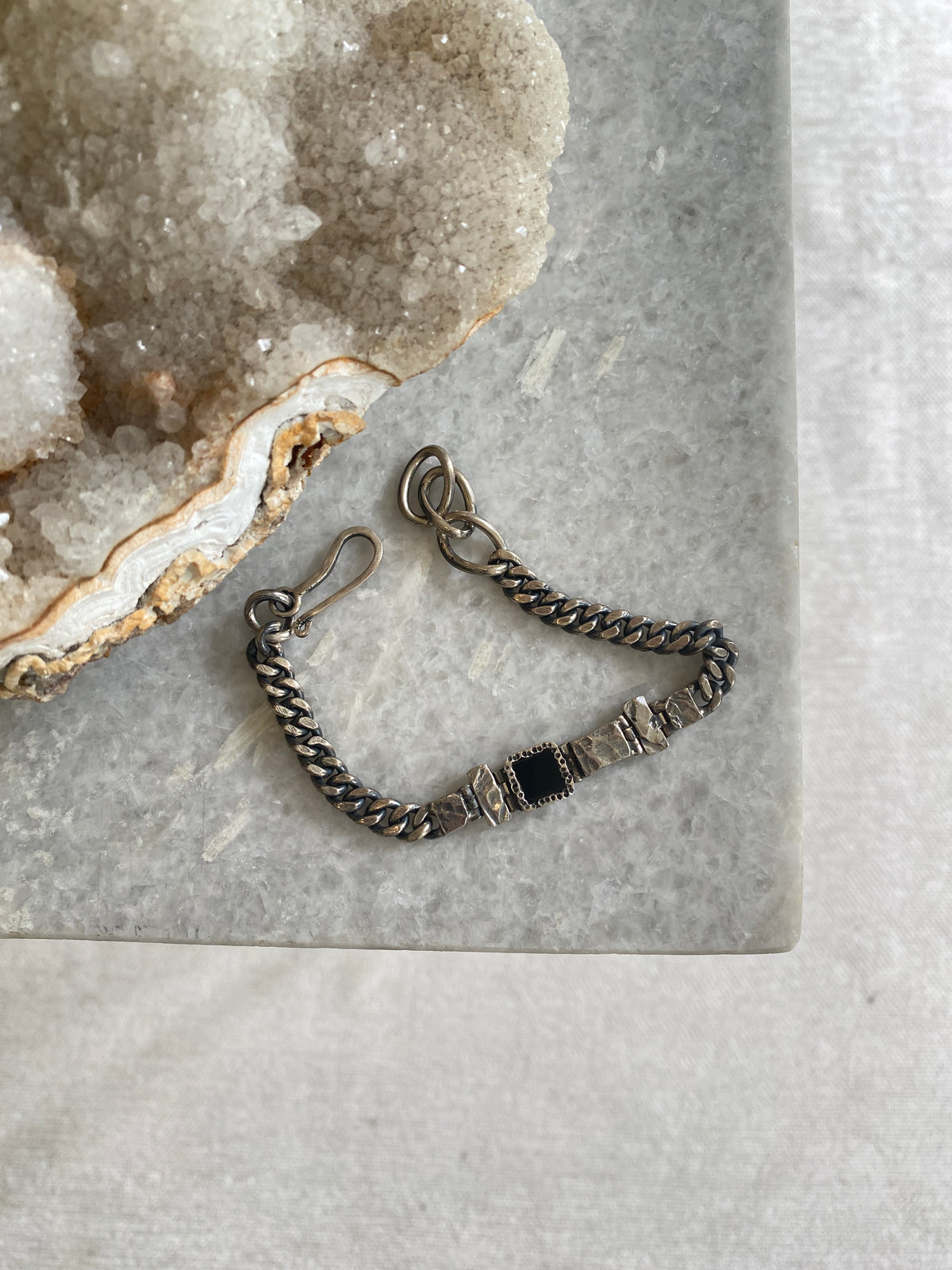 a blackened siler ad onyx bracelet sits on a marble bench