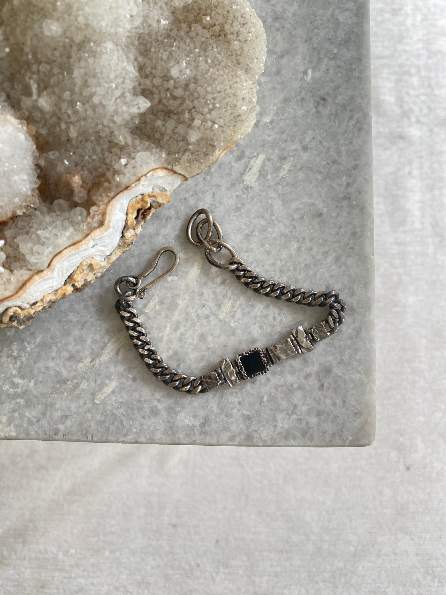 a blackened siler ad onyx bracelet sits on a marble bench