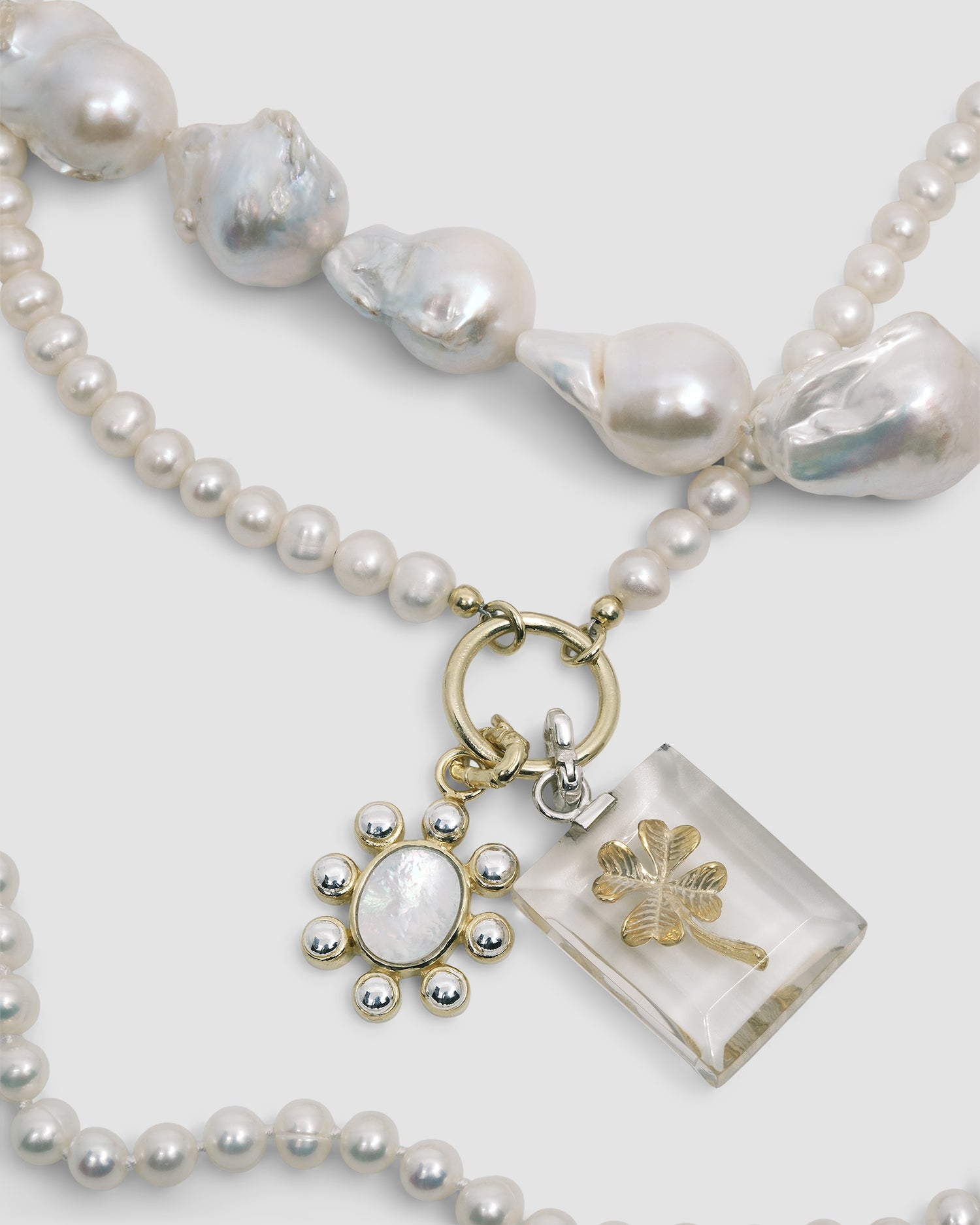 pearl necklaces with two charms attached - one a flower one a four leaf clover