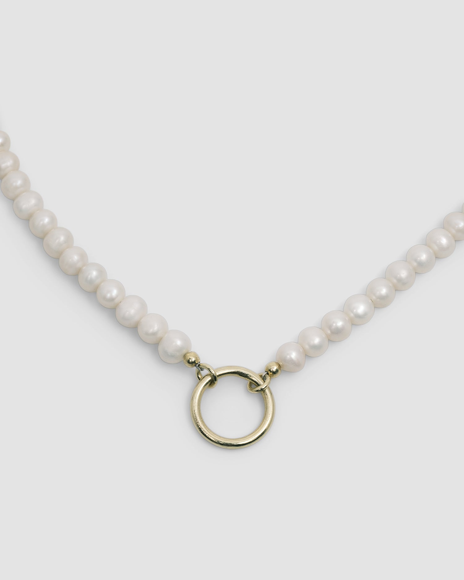 a pearl necklace with a gold ring for charms