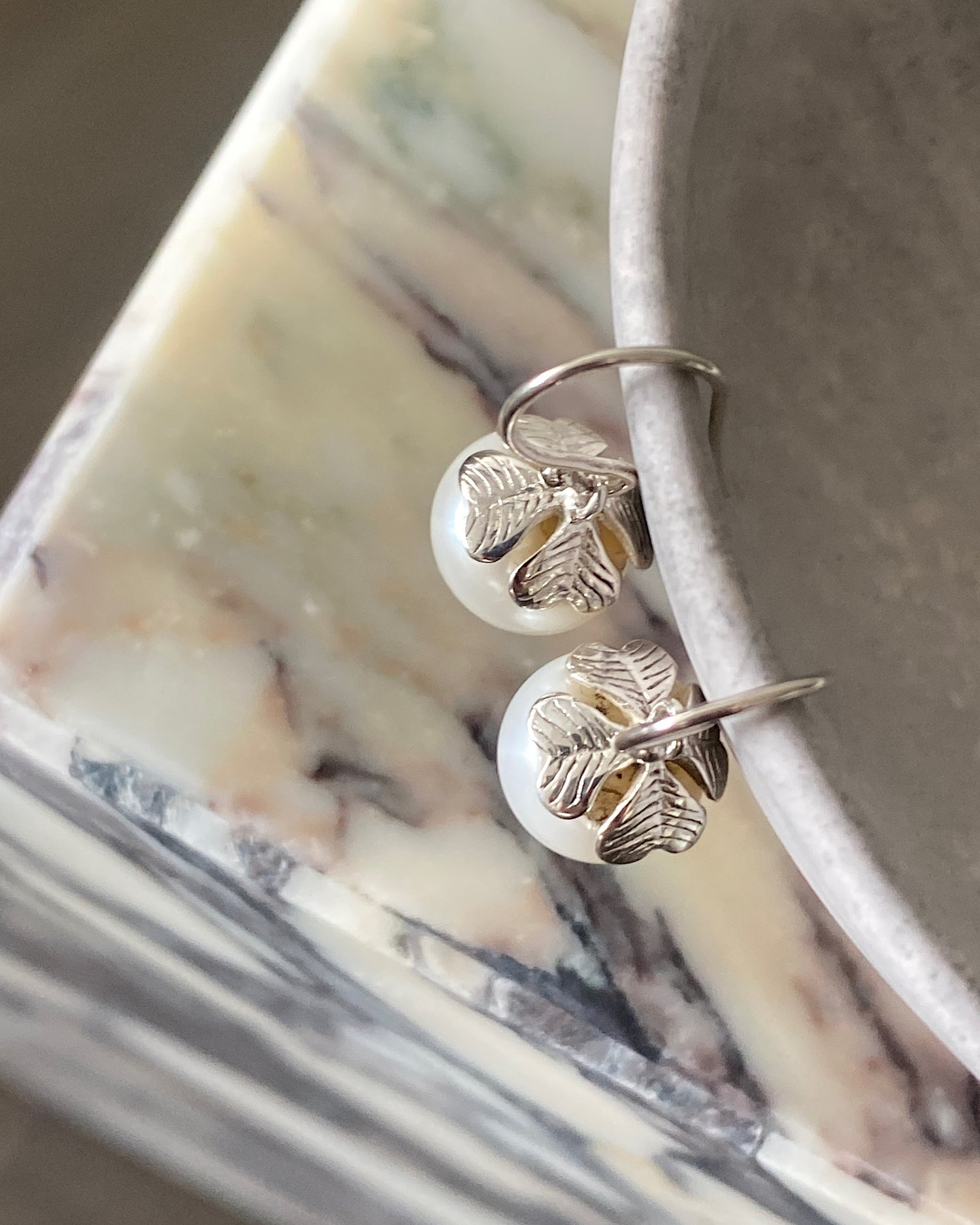 Silver hook earrings with pearls encased in a clover leaf top