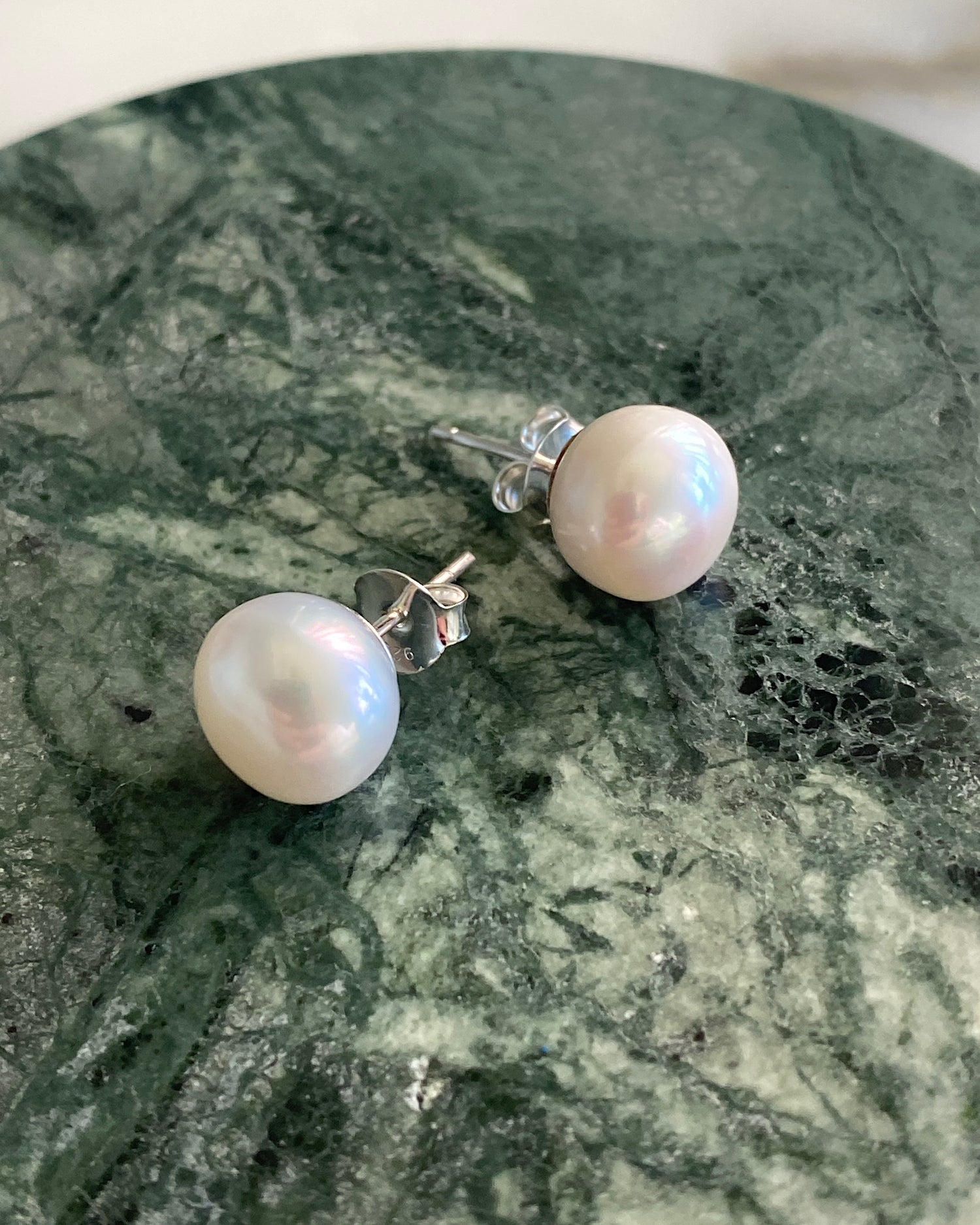 large pearl studs sit on green marble