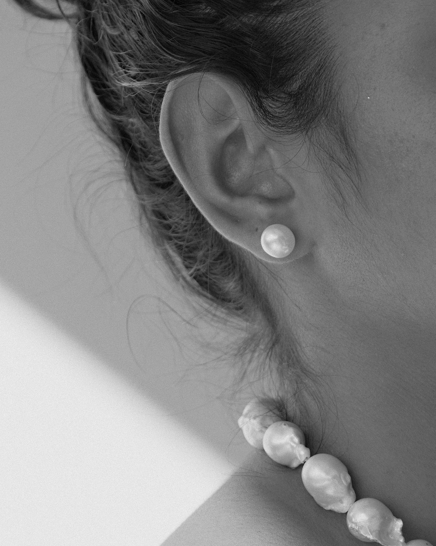 model wears a pearl stud earring and large short pearl necklace