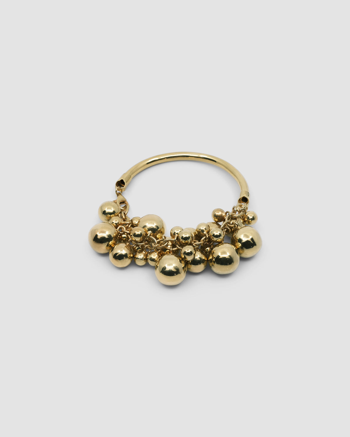 a gold bangle with a group of various shaped gold balls attached to half