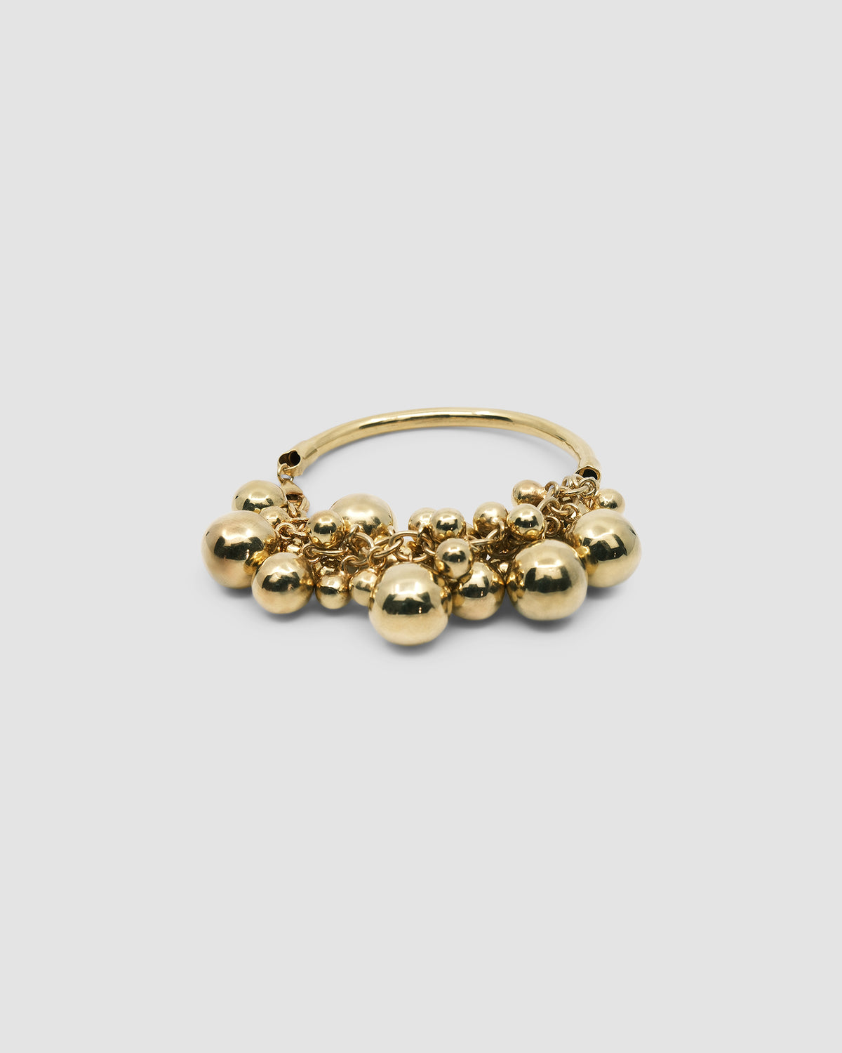 a gold bangle with a group of various shaped gold balls attached to half