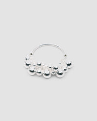 a silver bangle with a group of various shaped silver balls attached to half