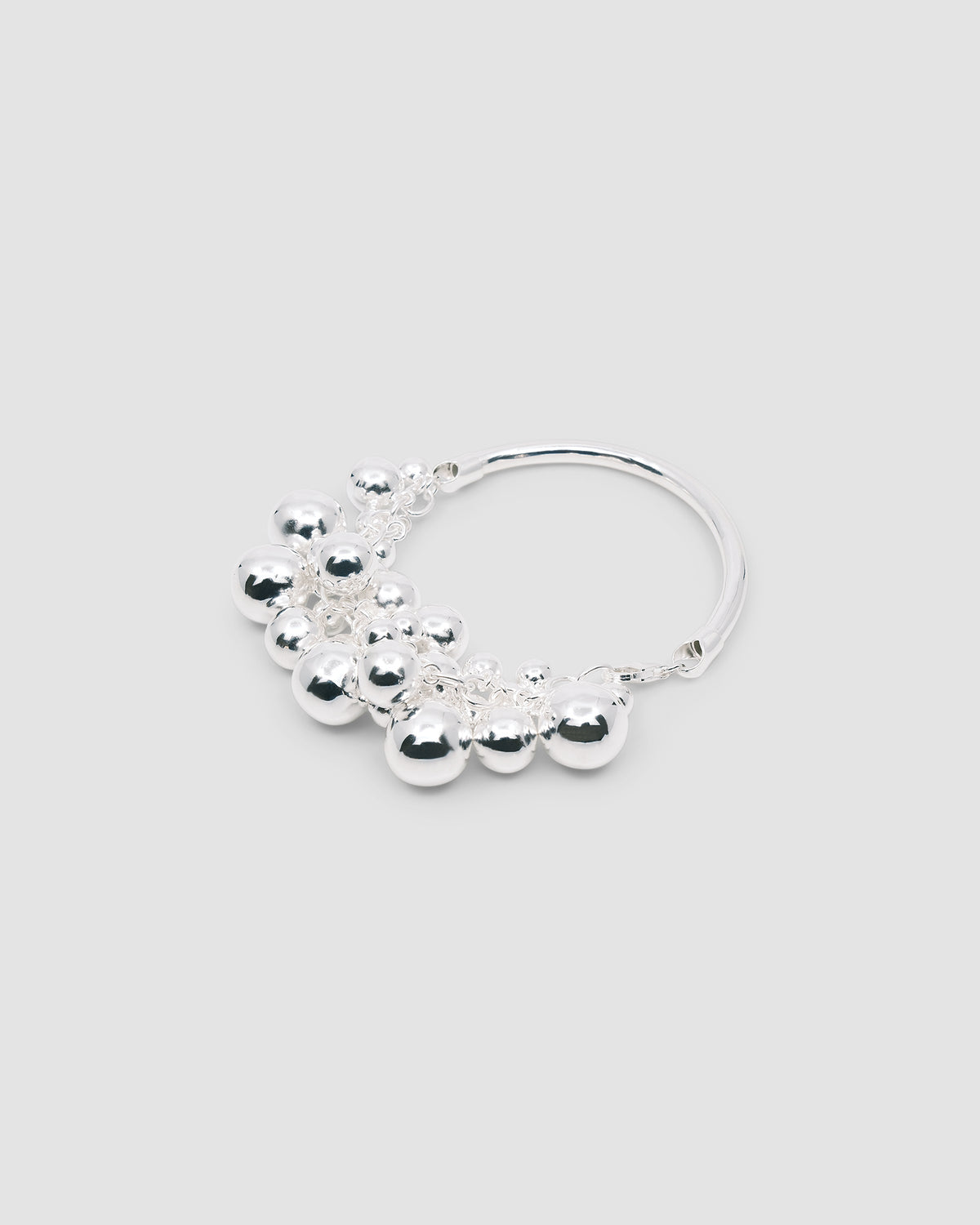 a silver bangle with a group of various shaped silver balls attached to half