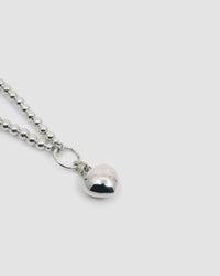 a ball necklace with a ring and a silver heart charm attached to it