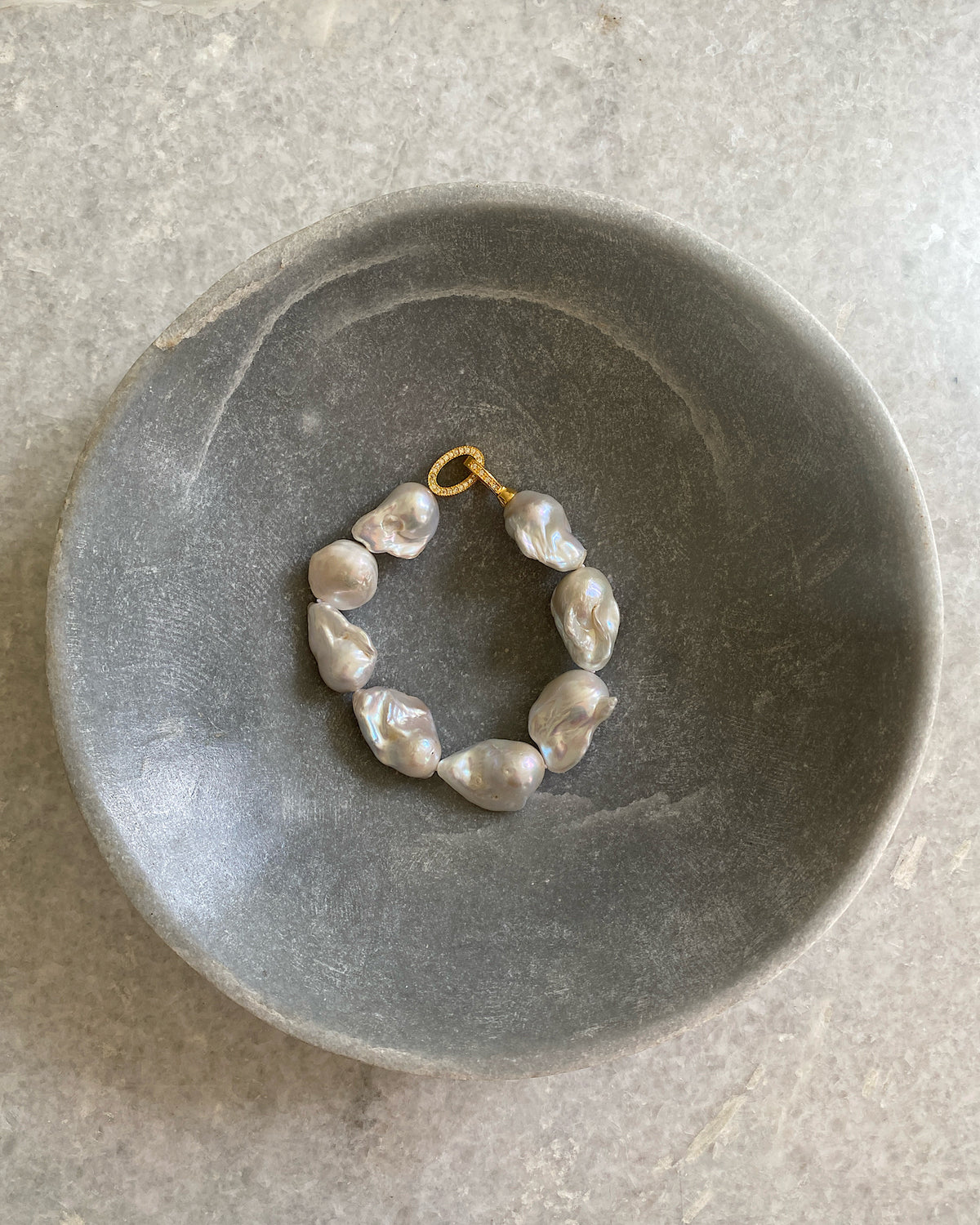 a medium size pearl bracelet sits on a bowl