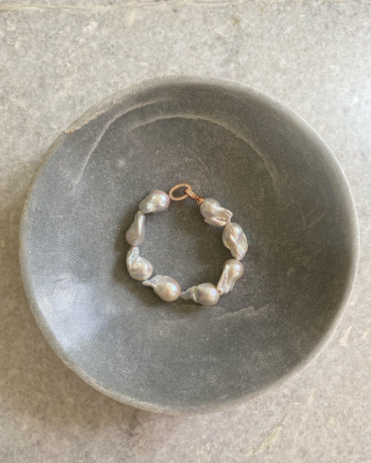 pearl bracelet with rose gold clasp sits in a bowl