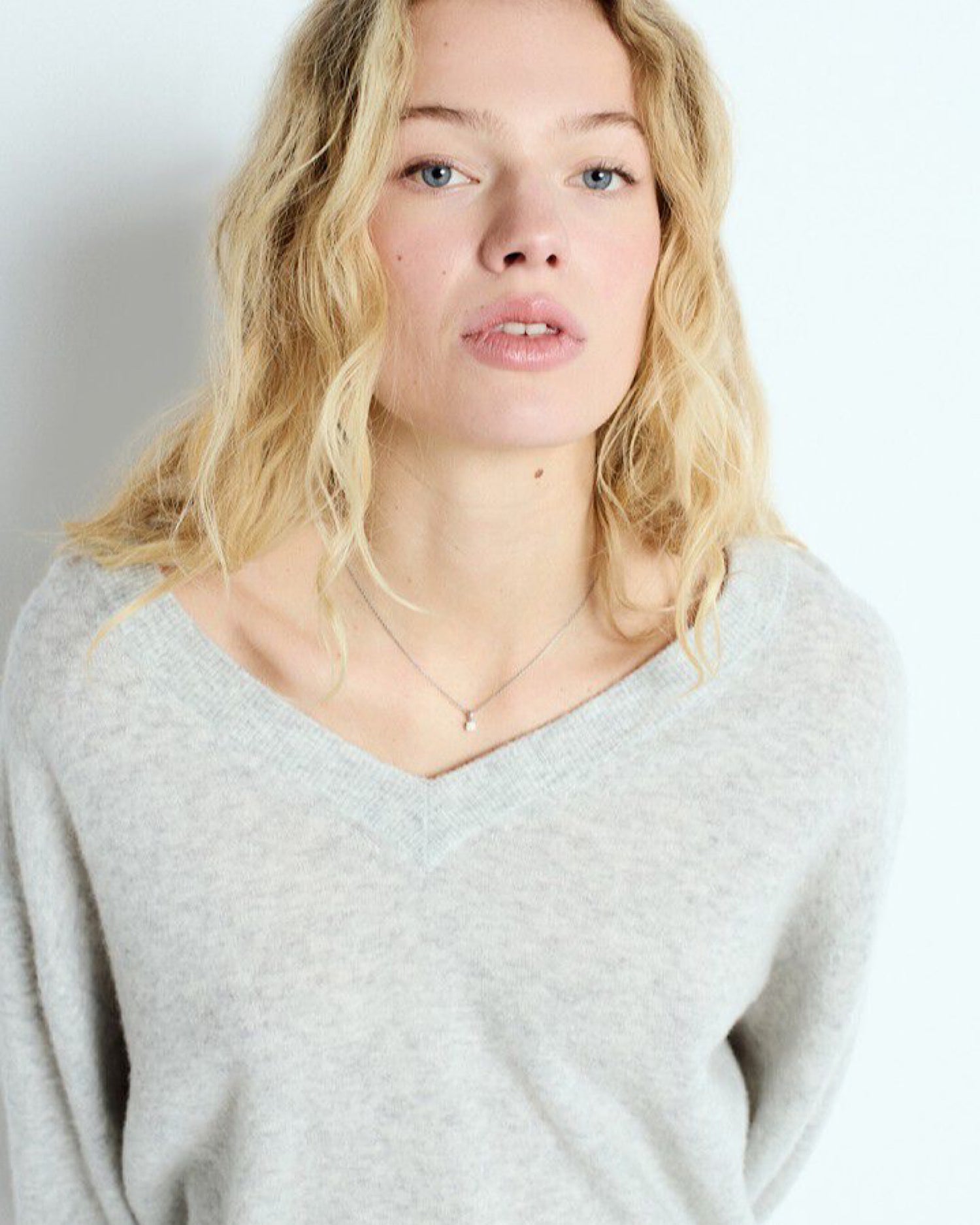 Model wears a v neck Heather grey Raxow Sweater from American Vintage available at The Pared Store
