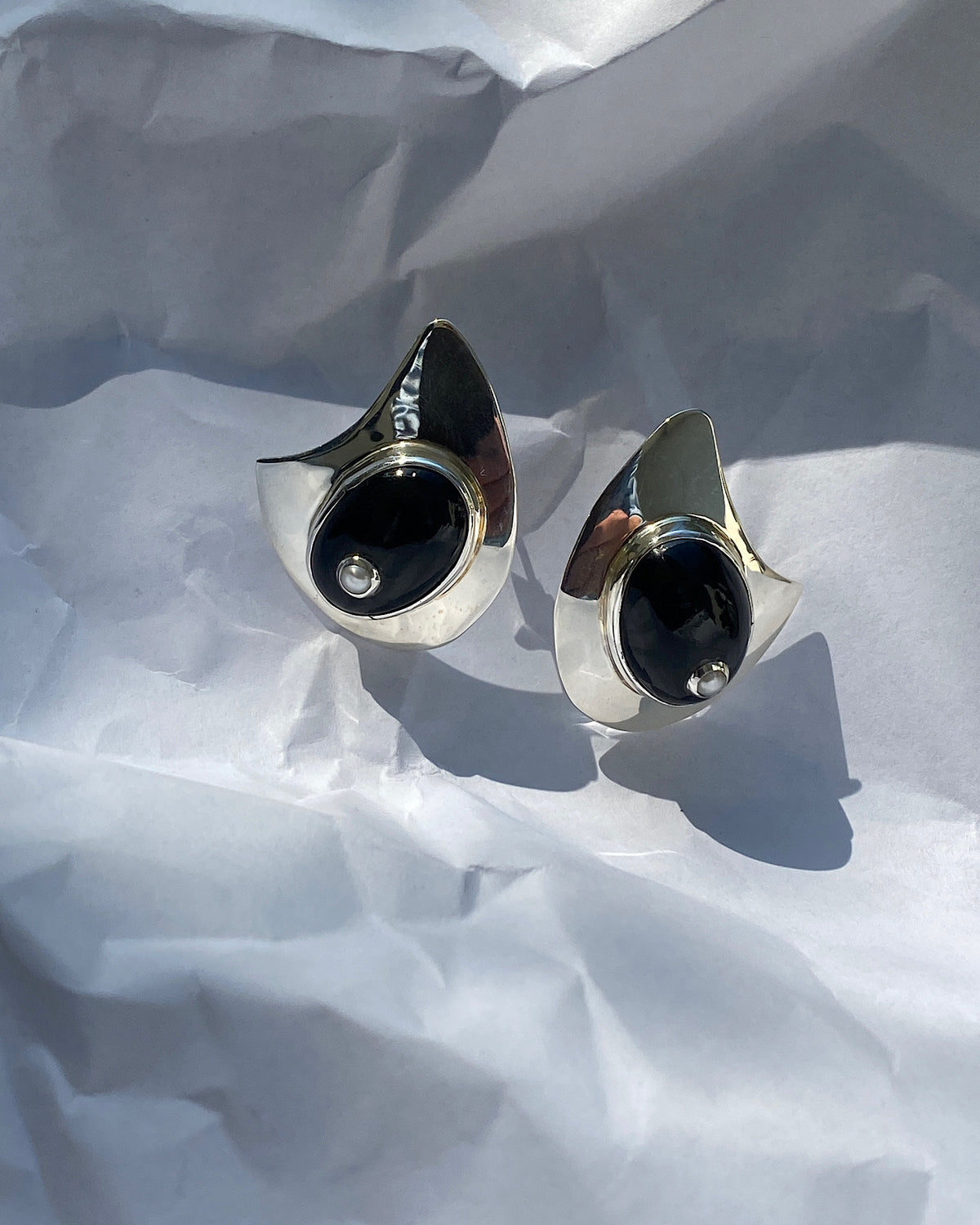 organic shaped silver earrings with a large onyx stone with a pearl centre