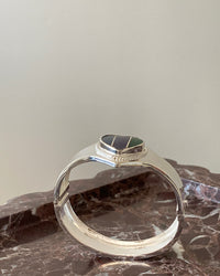 silver cuff bracelet with an inlaid heart striped blue, purple and green stone