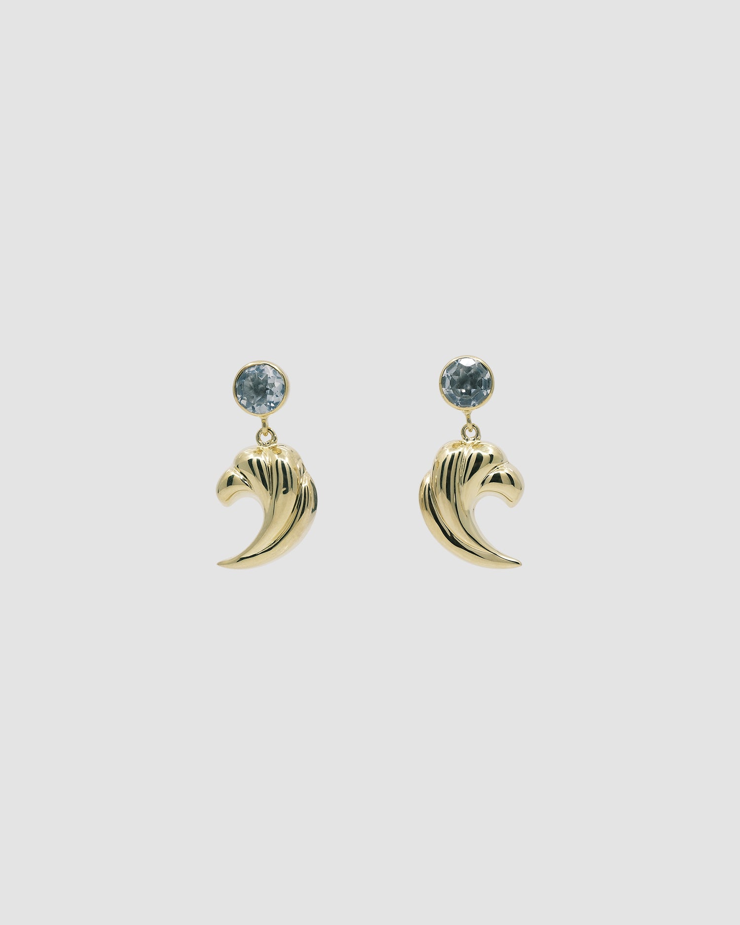 Crystal stud earrings with a gold wave charm dangling from them