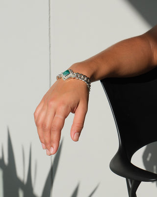 model wears a silver chain bracelet with a green square stone