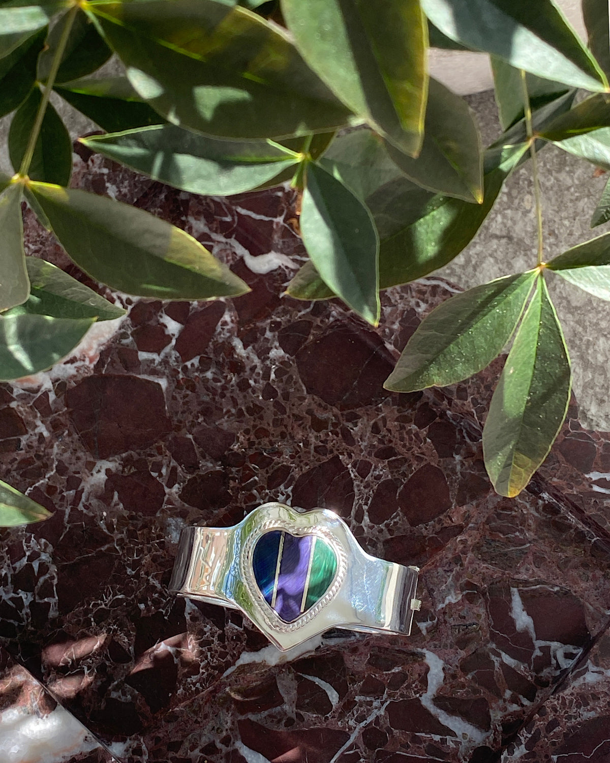 silver cuff bracelet with an inlaid heart striped blue, purple and green stone