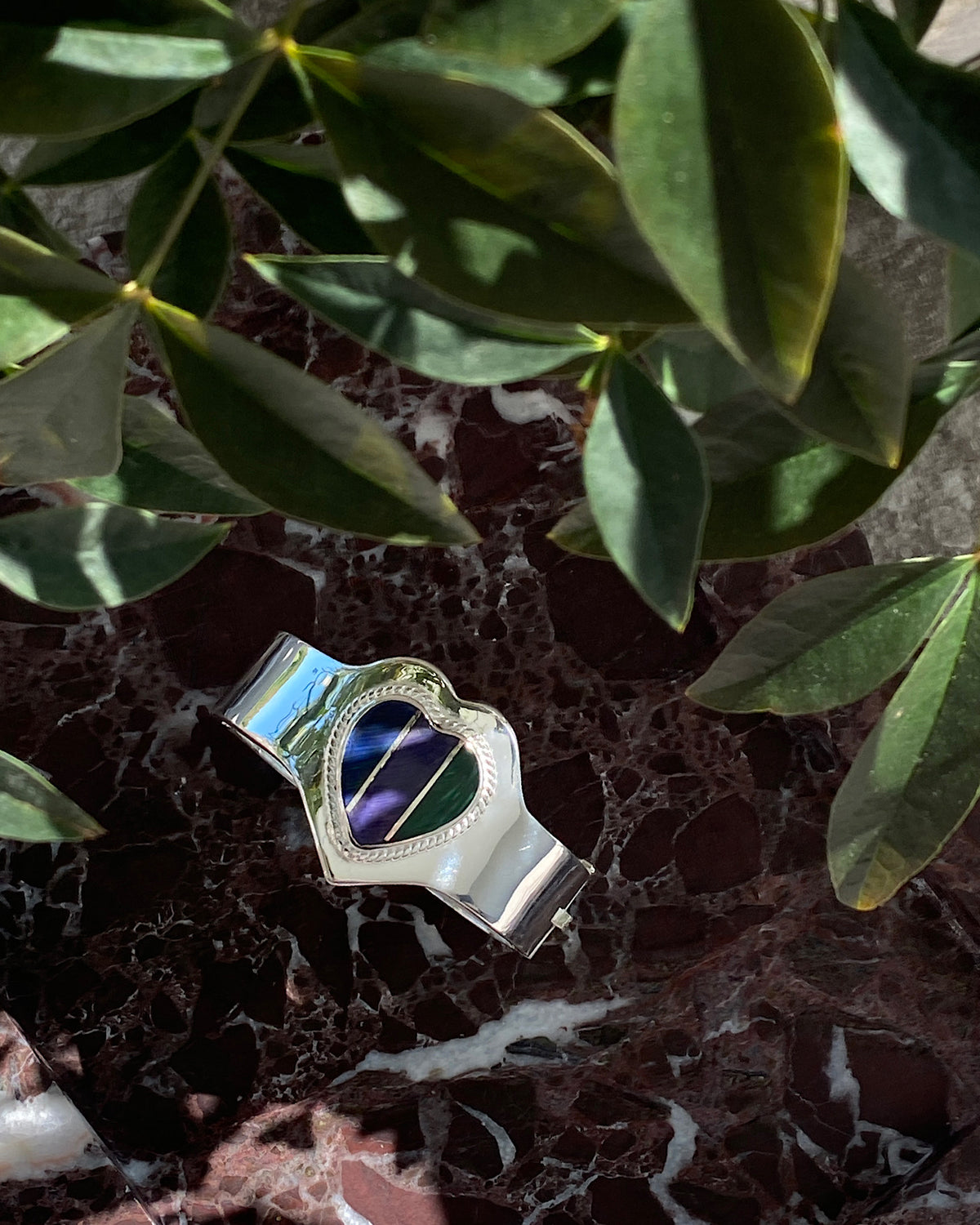 silver cuff bracelet with an inlaid heart striped blue, purple and green stone