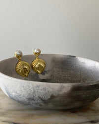 Pearl stud with gold shell like drop earring in a bowl