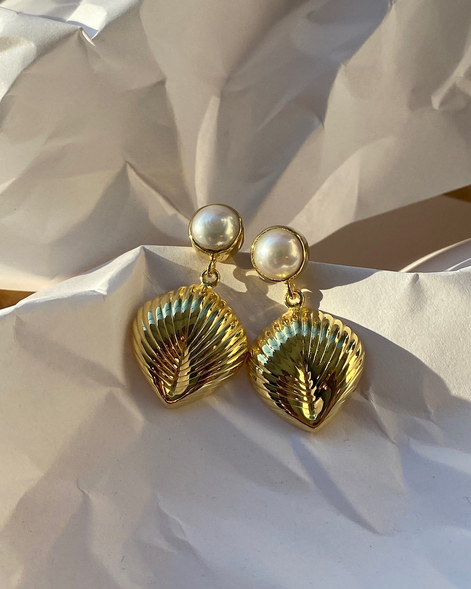 Pearl stud with gold shell like drop earring on paper