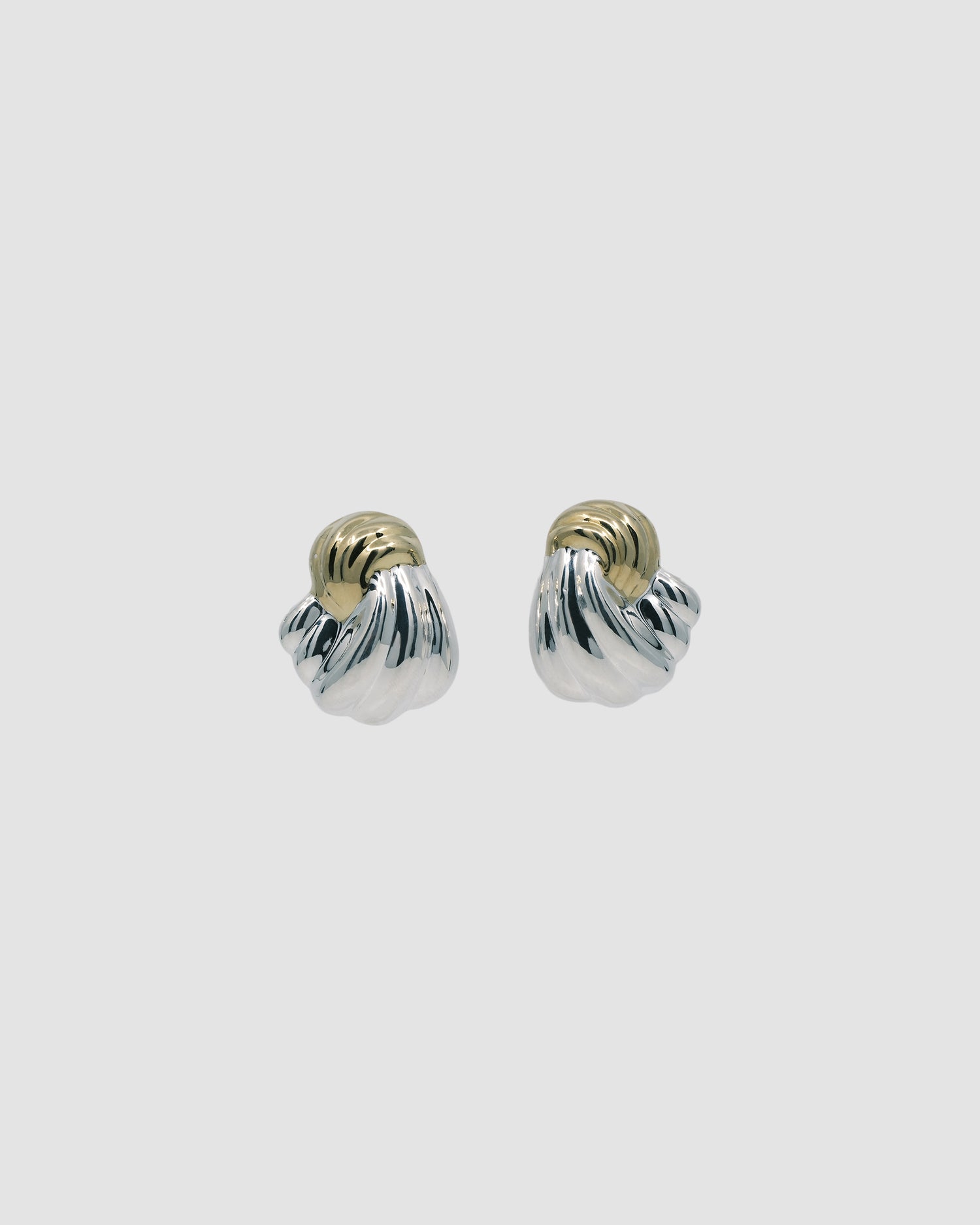 Twisted silver and gold earrings against a grey background