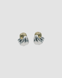 Twisted silver and gold earrings against a grey background